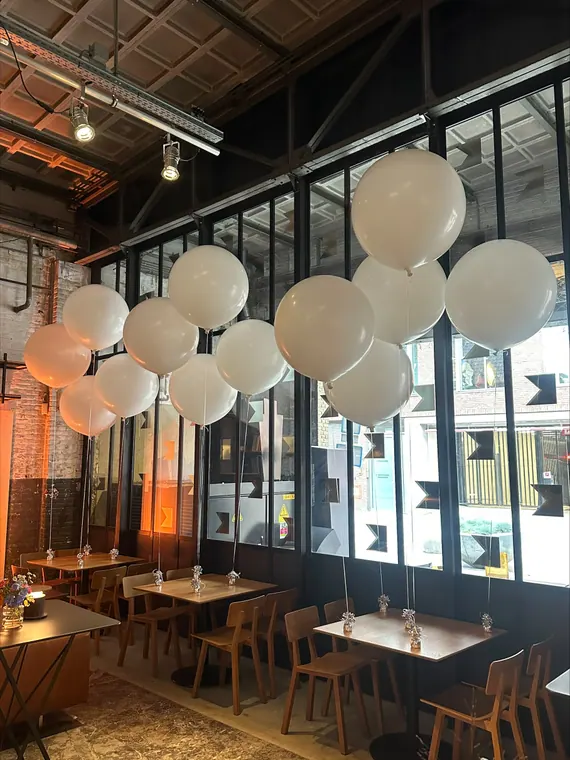 Witte heliumballonnen boven een restauranttafel