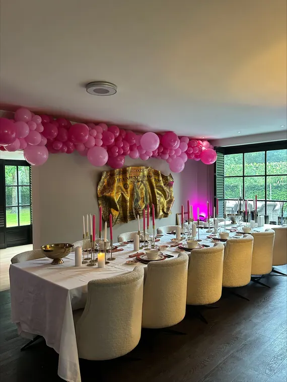 Roze ballonguirlande boven een feesttafel