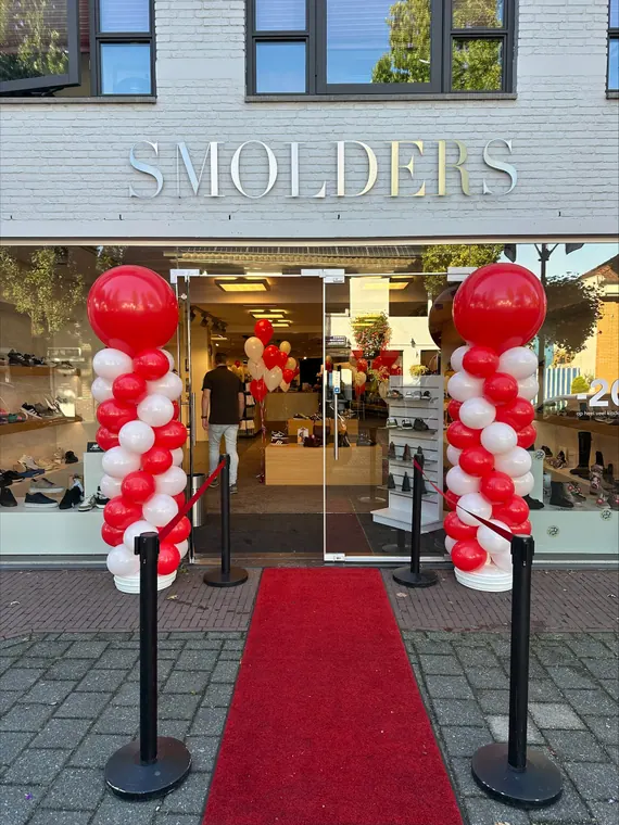 Rood-witte ballonpilaren bij een winkel