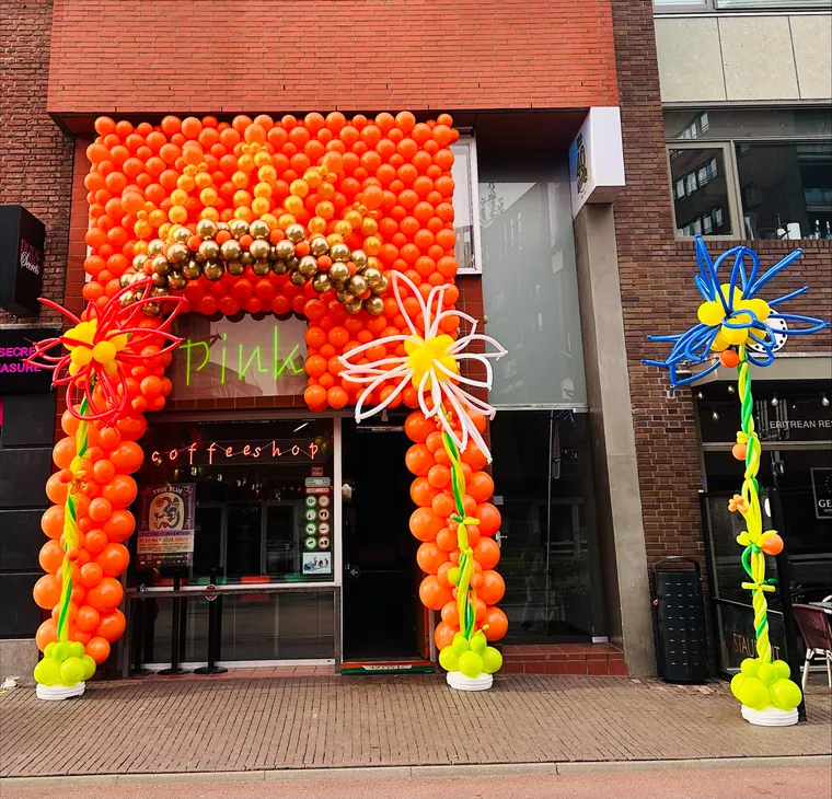 Rood-oranje ballonboog rond een winkelentree